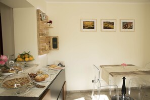 A breakfast buffet with various pastries and fruits, clear glassware, and a wooden shelf with decorative items. - BBuSS Country Club (Catanzaro)