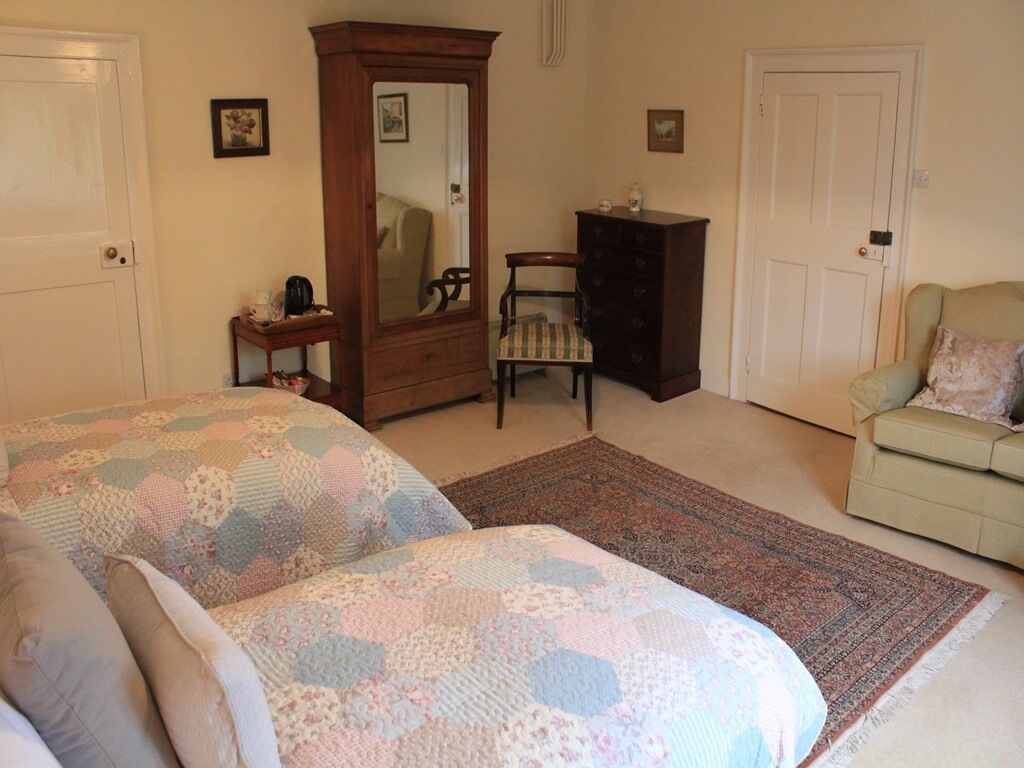 Un dormitorio con dos camas, un aparador, una silla, un espejo y una mesita.