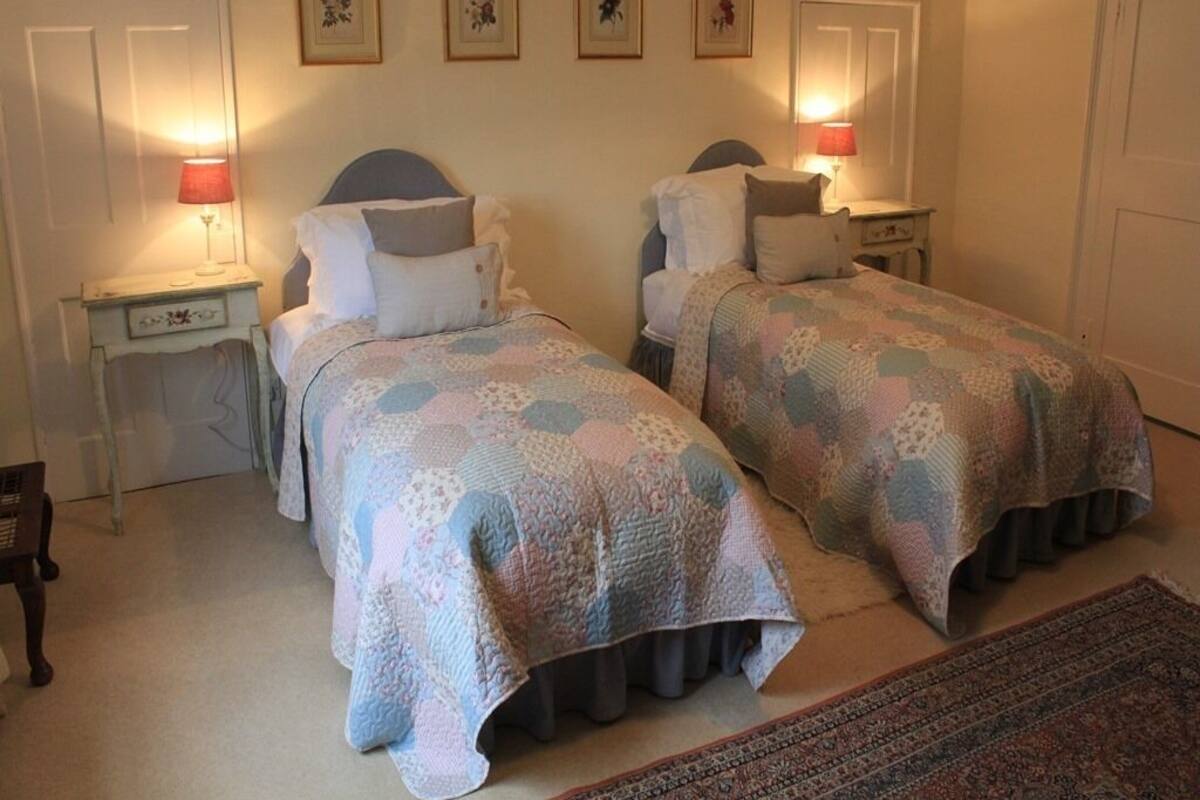 Une chambre à coucher avec deux lits, chacun doté d’une tête de lit et d’un pied de lit assortis, ainsi qu’une table de chevet avec une lampe.