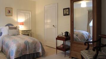 Une chambre à coucher comprenant un lit, une table de chevet, une lampe, une commode, une chaise et un miroir.