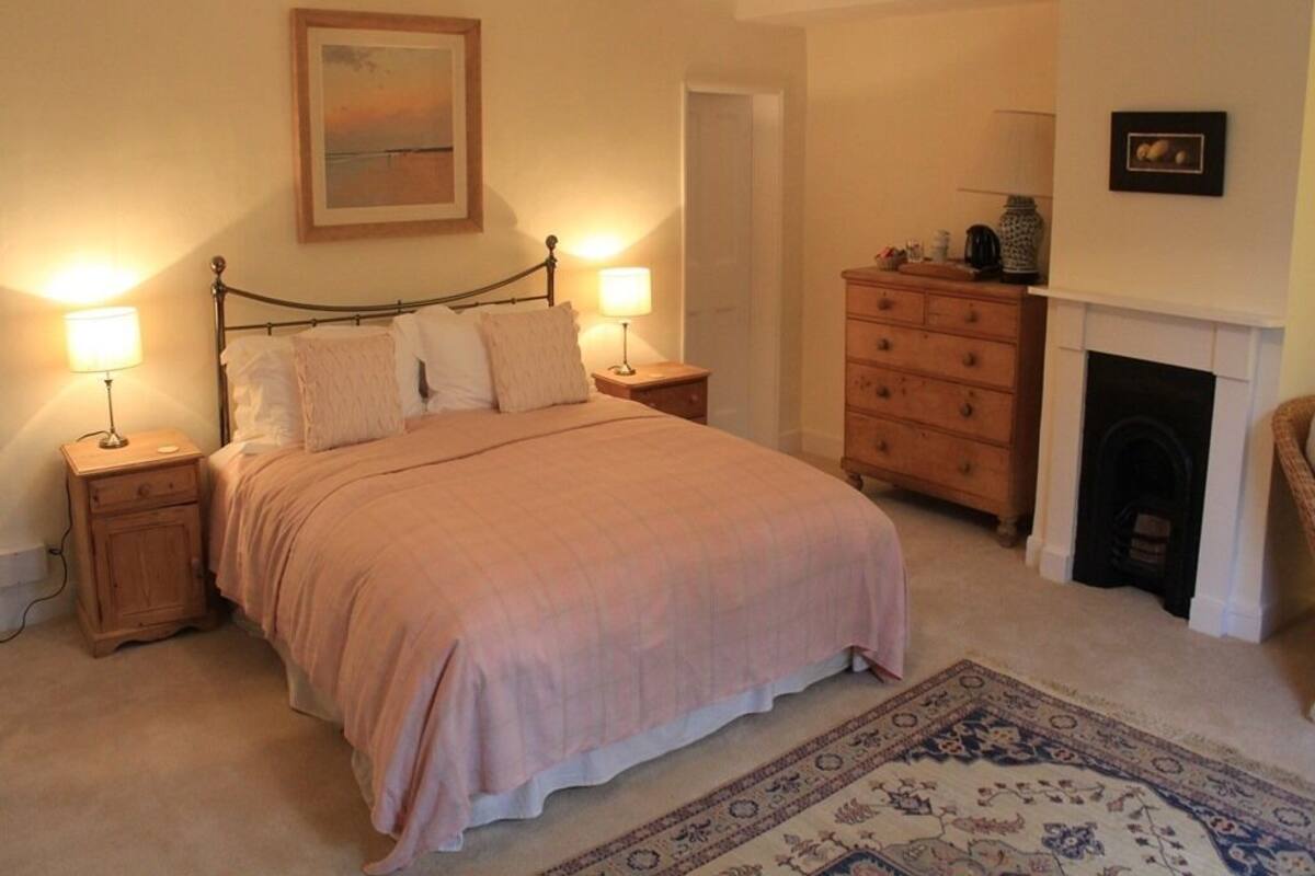 Une chambre à coucher avec un lit, des lampes de chevet, une commode, une cheminée et un tapis.