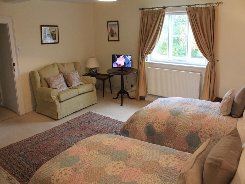 A bedroom with two beds, a sofa, a TV, and a window with curtains.