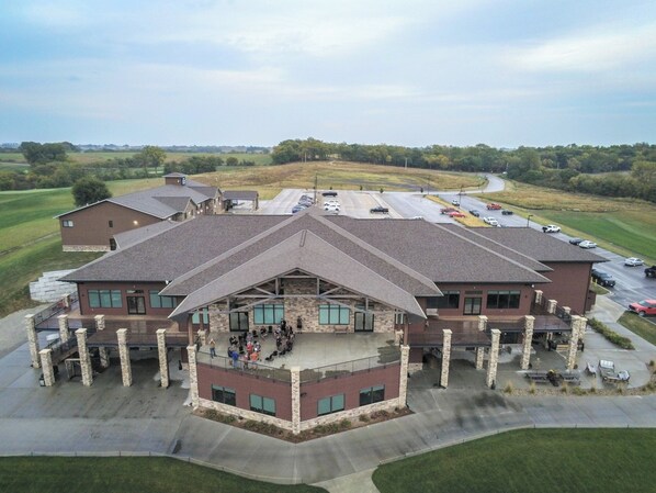 A multi-story building with a central courtyard, surrounded by parking and a golf course. - Cobblestone Inn & Suites - Maryville (Maryville)