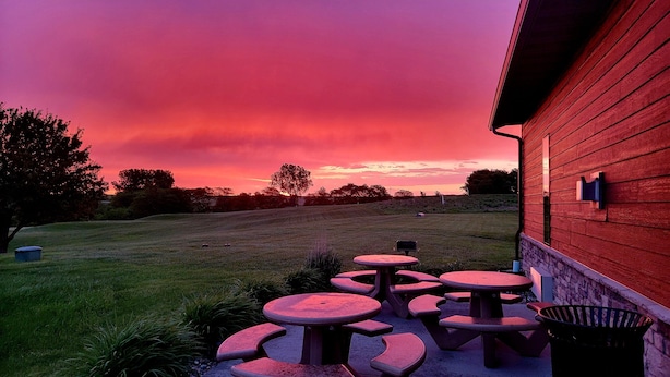 Une terrasse avec des tables de pique-nique et un terrain herbeux.