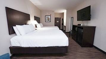 Una habitación de hotel con una cama grande, televisor, escritorio y cómoda.