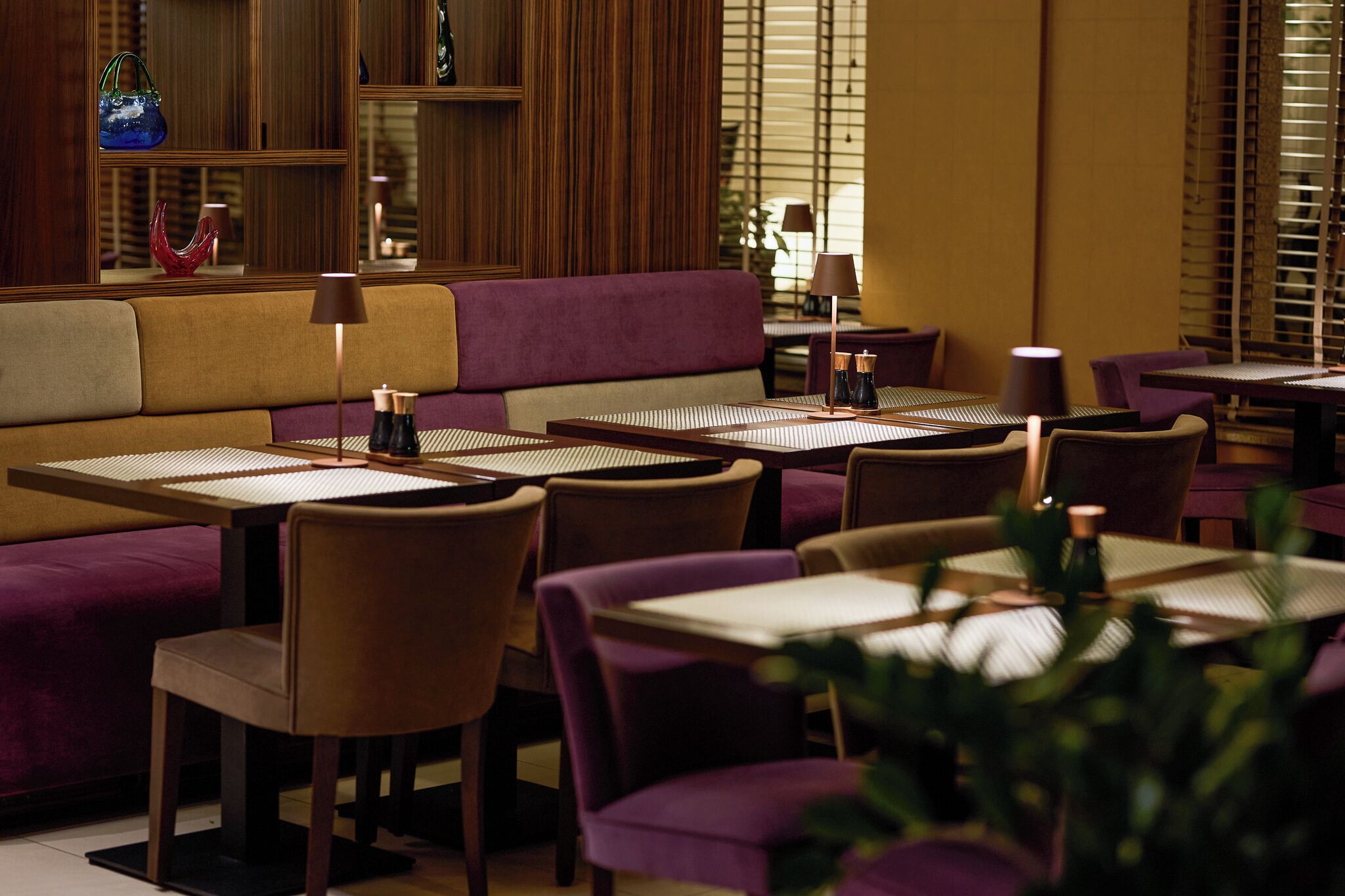 A restaurant with a booth seating area, individual tables, and chairs.