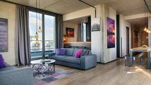 Una sala de estar moderna con un sofá gris, una mesita de centro y un comedor con un banco y una mesa.