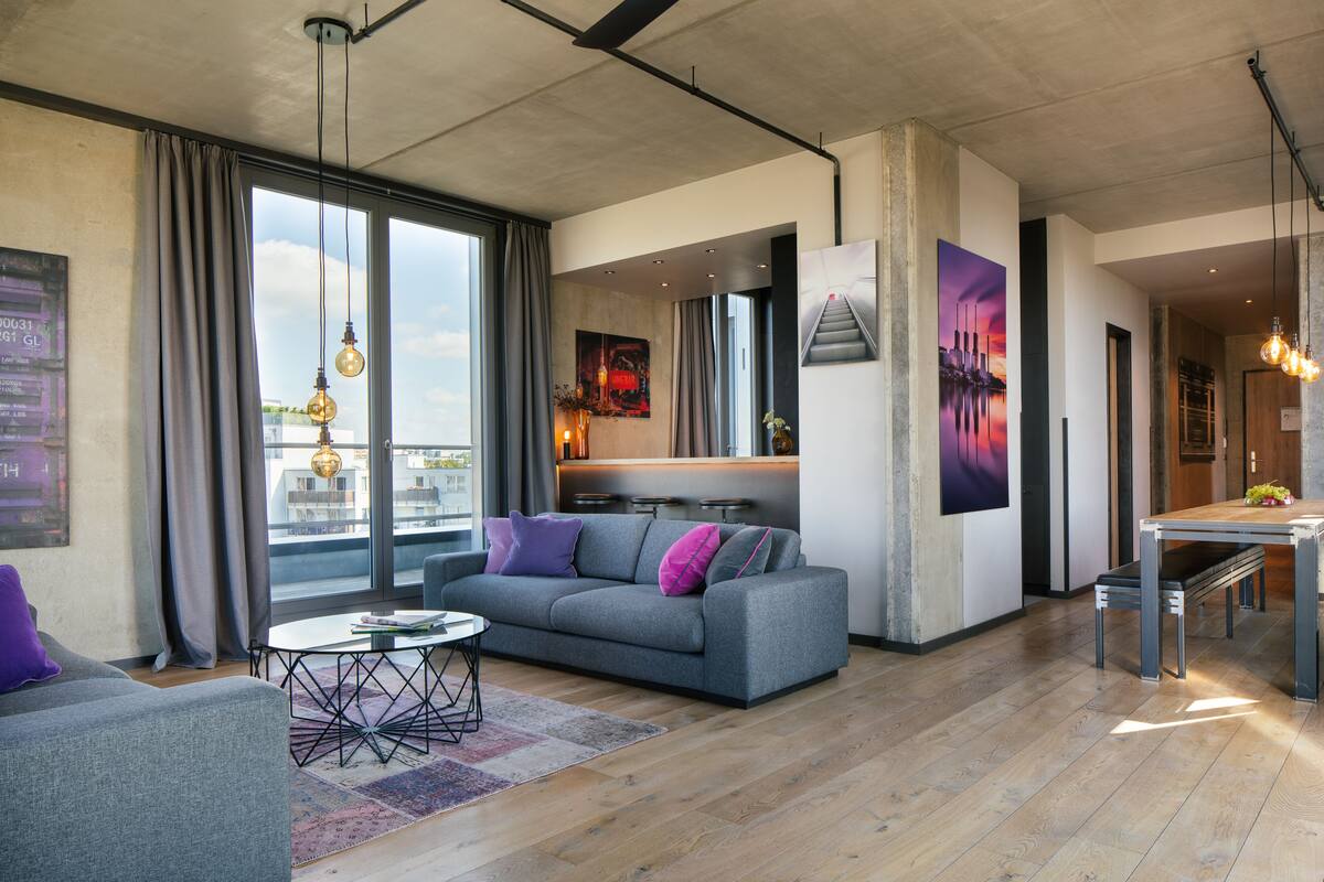 A modern living room with a grey sofa, a coffee table, and a dining area with a bench and table.