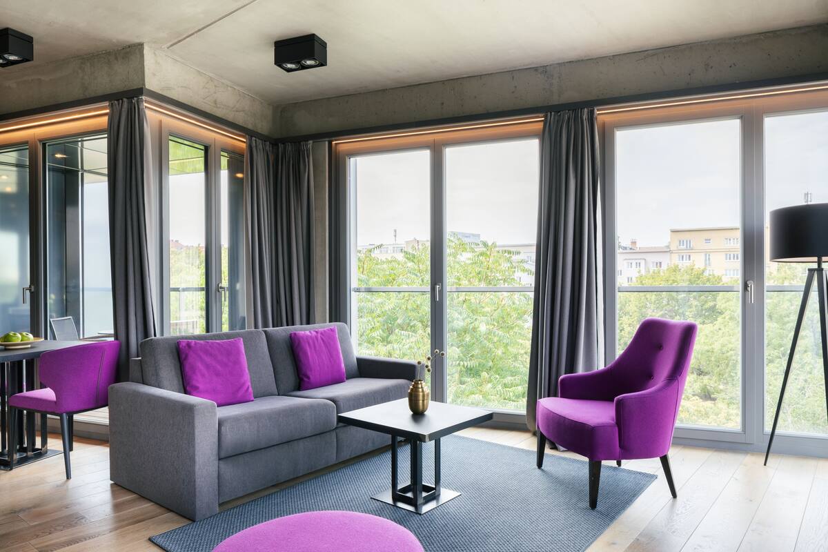 A modern living room with a grey sofa, purple armchairs, and a coffee table.