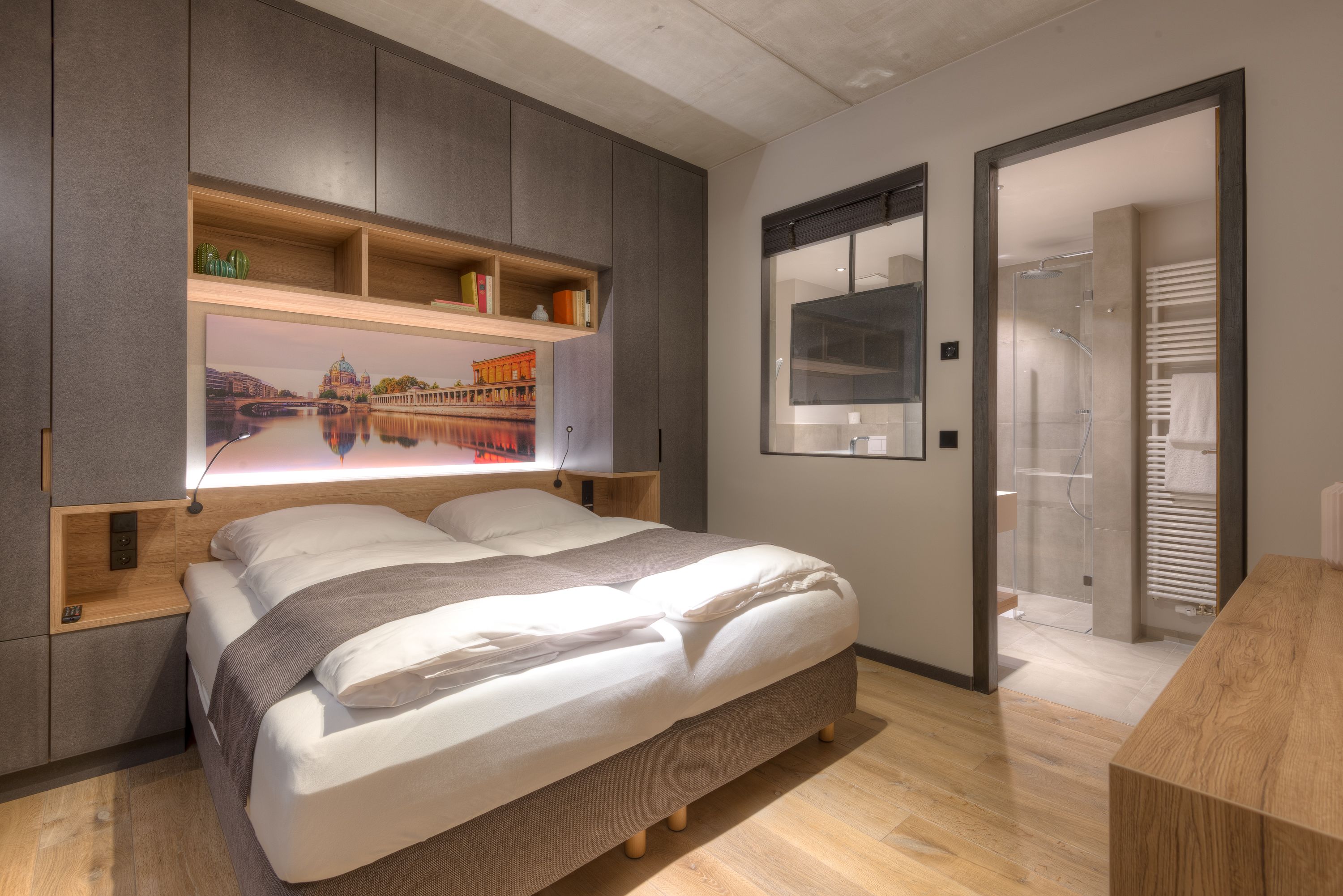 Une chambre moderne avec un grand lit, des étagères intégrées, une vue sur le paysage urbain et un dressing.