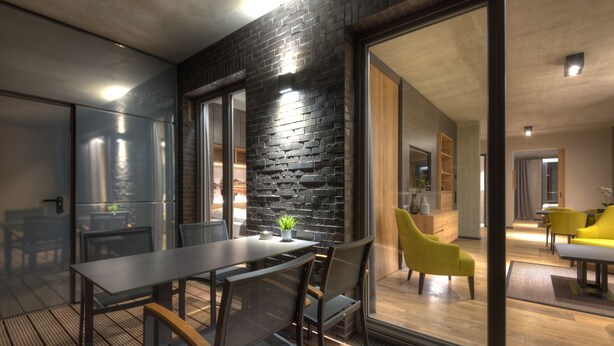 Un comedor moderno con pared de ladrillo negro, una pared divisoria de vidrio y piso de madera.