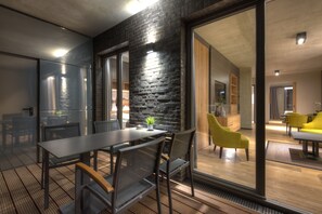 A modern dining area with a black brick wall, a glass partition, and a wooden floor.