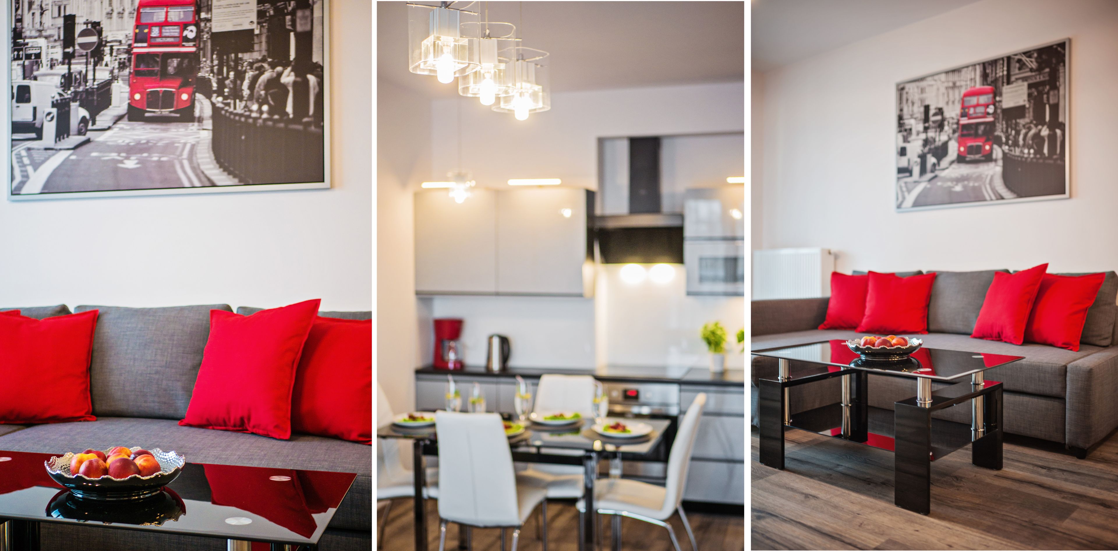 Ein modernes Wohnzimmer mit grauem Sofa und roten Kissen, ein Essbereich mit weißem Tisch und Stühlen sowie eine Küche mit modernen Geräten.