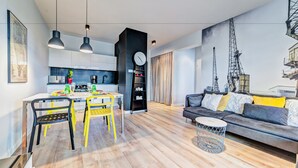 A modern living room with a sofa and a dining area with chairs and a table. - Apartamenty Homely Place City (Poznan)
