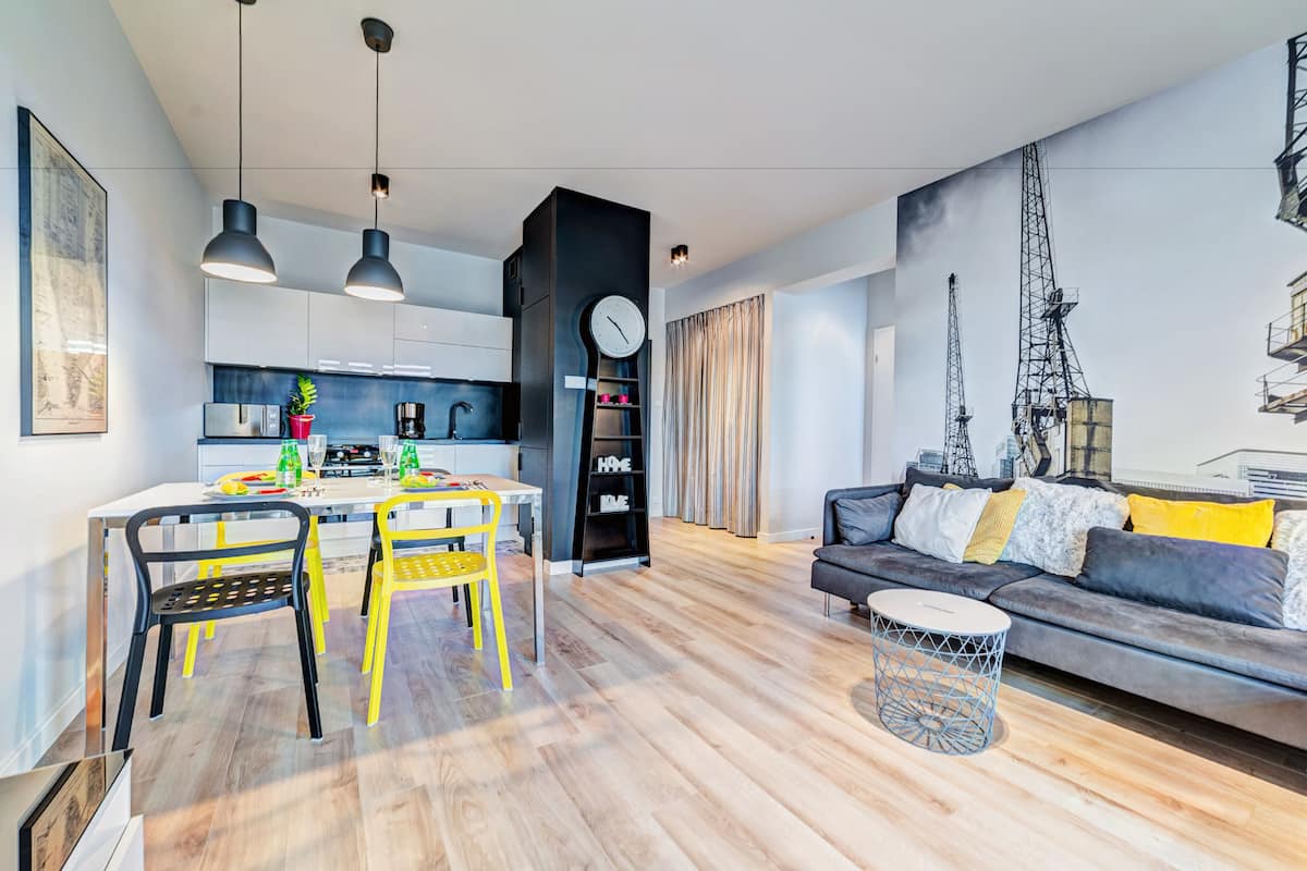 A modern living room with a sofa and a dining area with chairs and a table.