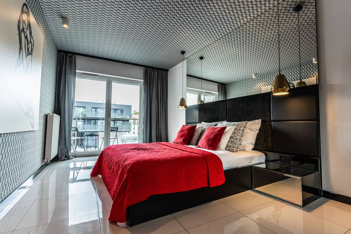 A modern bedroom with a large bed, a glass coffee table, and a view of the city.