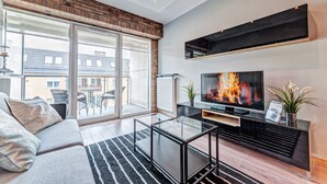 A modern living room with a sofa, glass coffee table, and a flat-screen TV. - Apartamenty Homely Place City (Poznan)