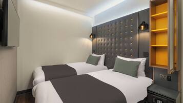 Hotelkamer met twee bedden, een modern hoofdbord, bedlampen, een inbouwkast en een bedieningspaneel.