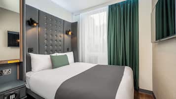 Quarto de hotel moderno com uma cama grande, cabeceira com iluminação, mesa de cabeceira com telefone e uma janela ampla com cortinas.