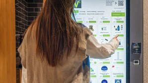 A person interacting with a vending machine labeled "POINT.a HOTELS" by Vendologi, featuring a touchscreen interface for selecting items. - Point A London Shoreditch (London)