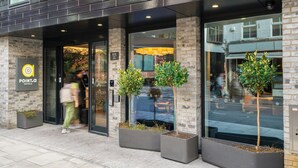 The entrance of Point A Hotels with a modern brick facade, large windows, and potted plants. - Point A London Shoreditch (London)