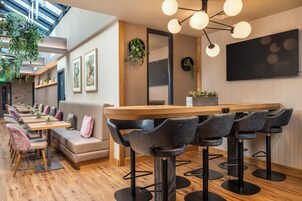 Eine moderne Bar mit einer langen Holztresen, mehreren Barhocker und einer Sitzgruppe mit gepolsterten Bänken.