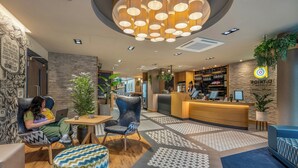 A hotel lobby with a reception desk, seating area, and a patterned floor. - Point A London Shoreditch (London)