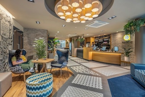 Eine Hotelhalle mit Empfangsschalter, Sitzgelegenheiten und einem gemusterten Boden.