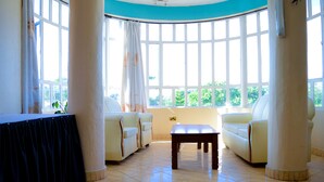 A room with a table, two sofas, and large windows. - Stardom Hotel (Nairobi)