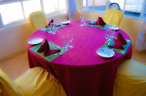 A round table with a vibrant pink tablecloth, surrounded by yellow chairs. - Stardom Hotel (Nairobi)