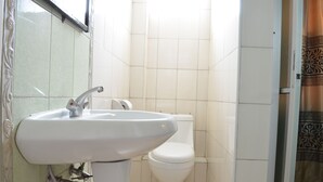 A bathroom with a white sink, toilet, and tiled walls. - Royal City Hotel (Kisumu)