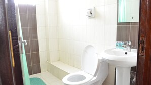A bathroom with a toilet, sink, and shower area. - Royal City Hotel (Kisumu)