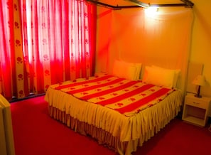 Une chambre d’hôtel avec un lit, des rideaux, une table de chevet et une lampe.