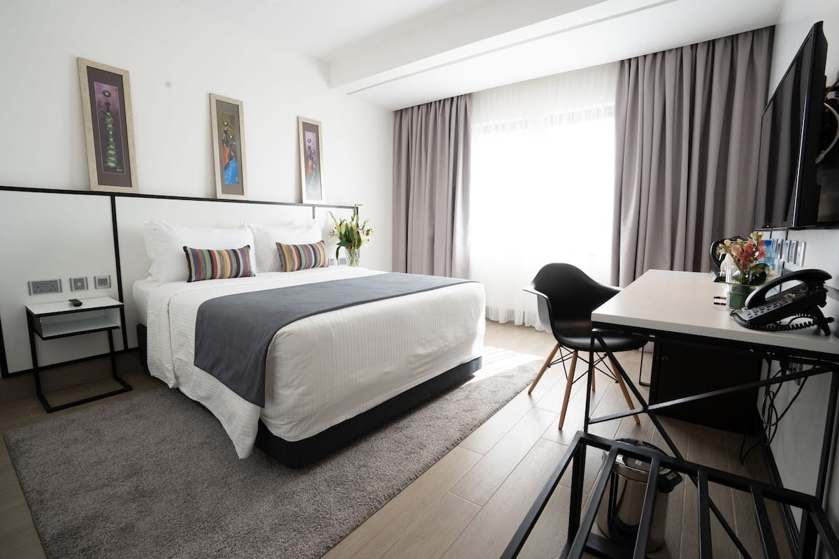 Una habitación de hotel moderna con una cama grande, un escritorio y una televisión.