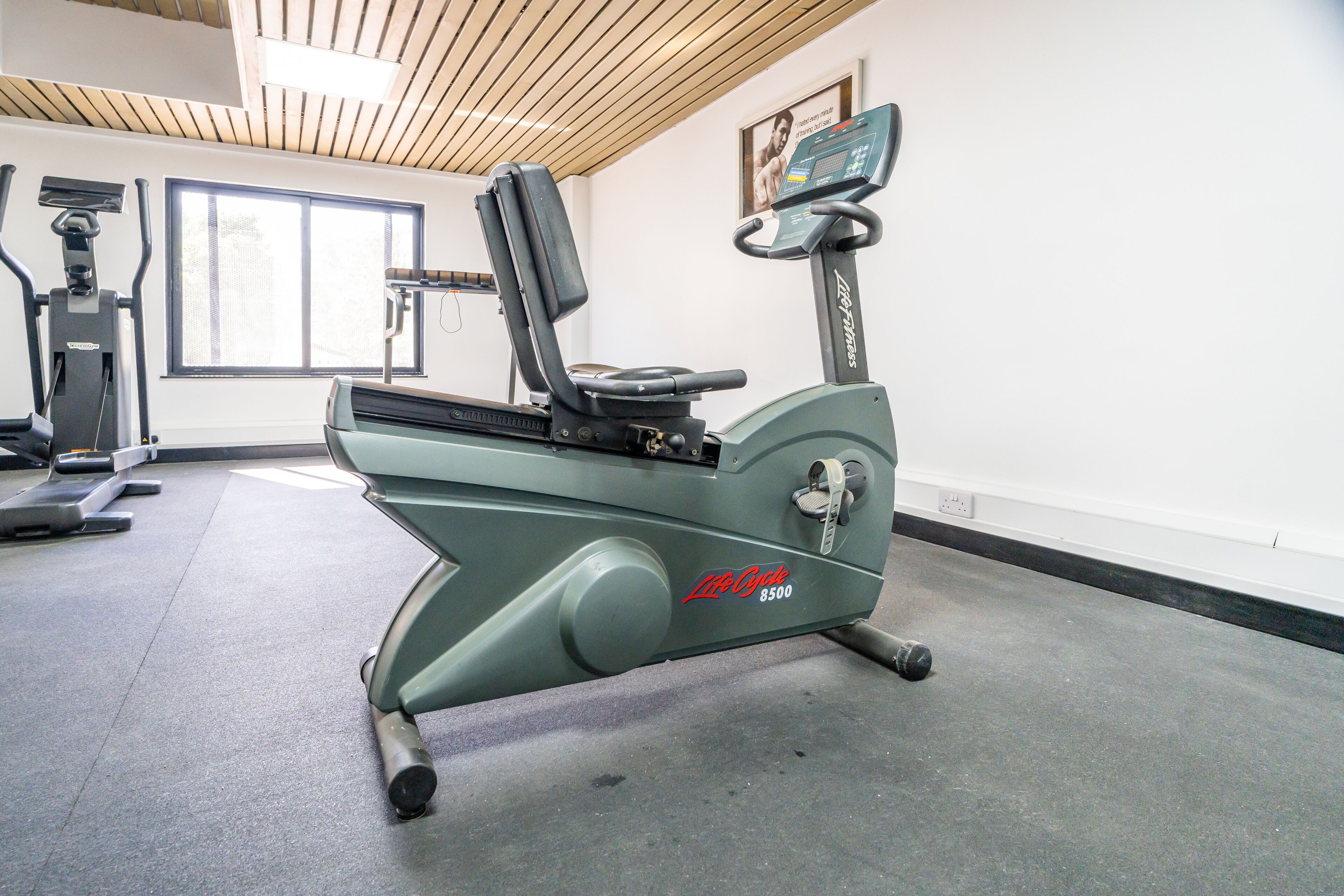 A stationary bike, a treadmill, and a window in a gym.