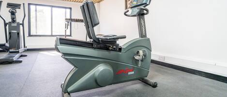 A stationary bike, a treadmill, and a window in a gym.