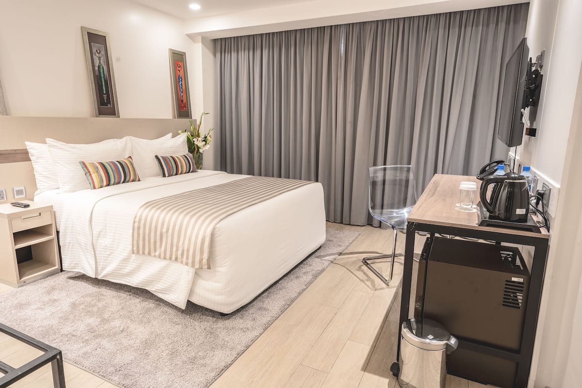 Una habitación de hotel con cama, mesita de noche y escritorio con silla.