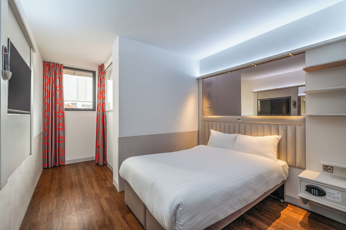 A hotel room with a bed, a TV, a microwave, and a built-in wardrobe.