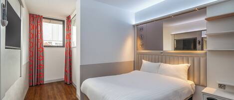 Habitación de hotel con cama, televisor, microondas y armario empotrado.
