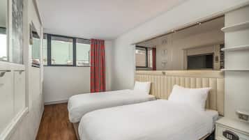 Een hotelkamer met twee bedden, een televisie, een minibar en een raam met uitzicht.