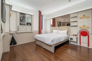 Una habitación de hotel moderna con una cama, una mesita de noche, un espejo y un armario.