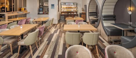 Un intérieur de restaurant moderne avec des tables en bois, des chaises à motifs et un comptoir pour le petit-déjeuner.