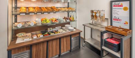 A breakfast buffet with various food items and a sign indicating breakfast hours.