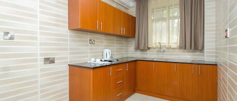 Una cocina moderna con armarios de madera, encimera negra y ventana con cortinas.
