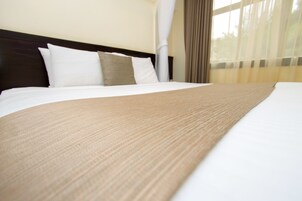 Una cama bien hecha con una colcha marrón y almohadas blancas en una habitación de hotel.