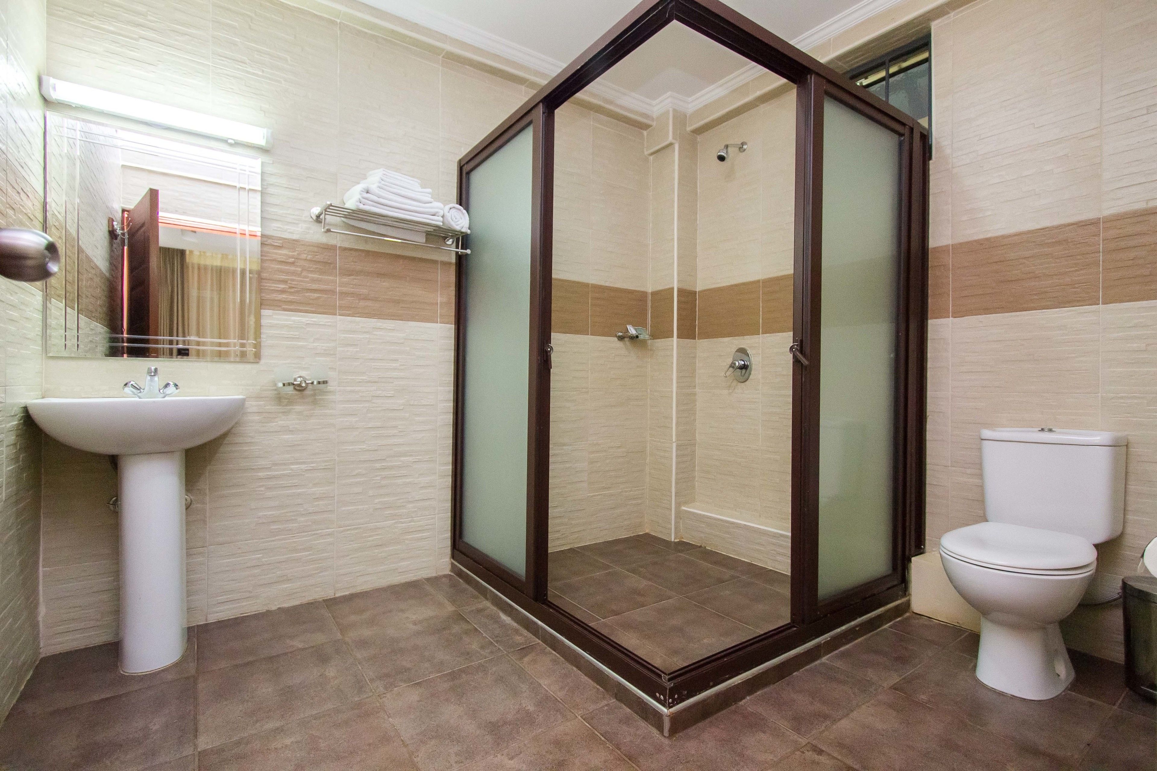A bathroom with a glass-enclosed shower, a sink, and a toilet.
