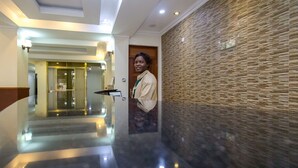 A hotel corridor with a polished floor, a reception desk, and a textured wall. - Pinecone Hotel (Kisumu)