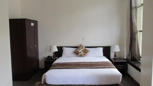 Ein Hotelzimmer mit einem Bett, zwei Nachttischen, einem Kleiderschrank und einem fenster mit Vorhängen.