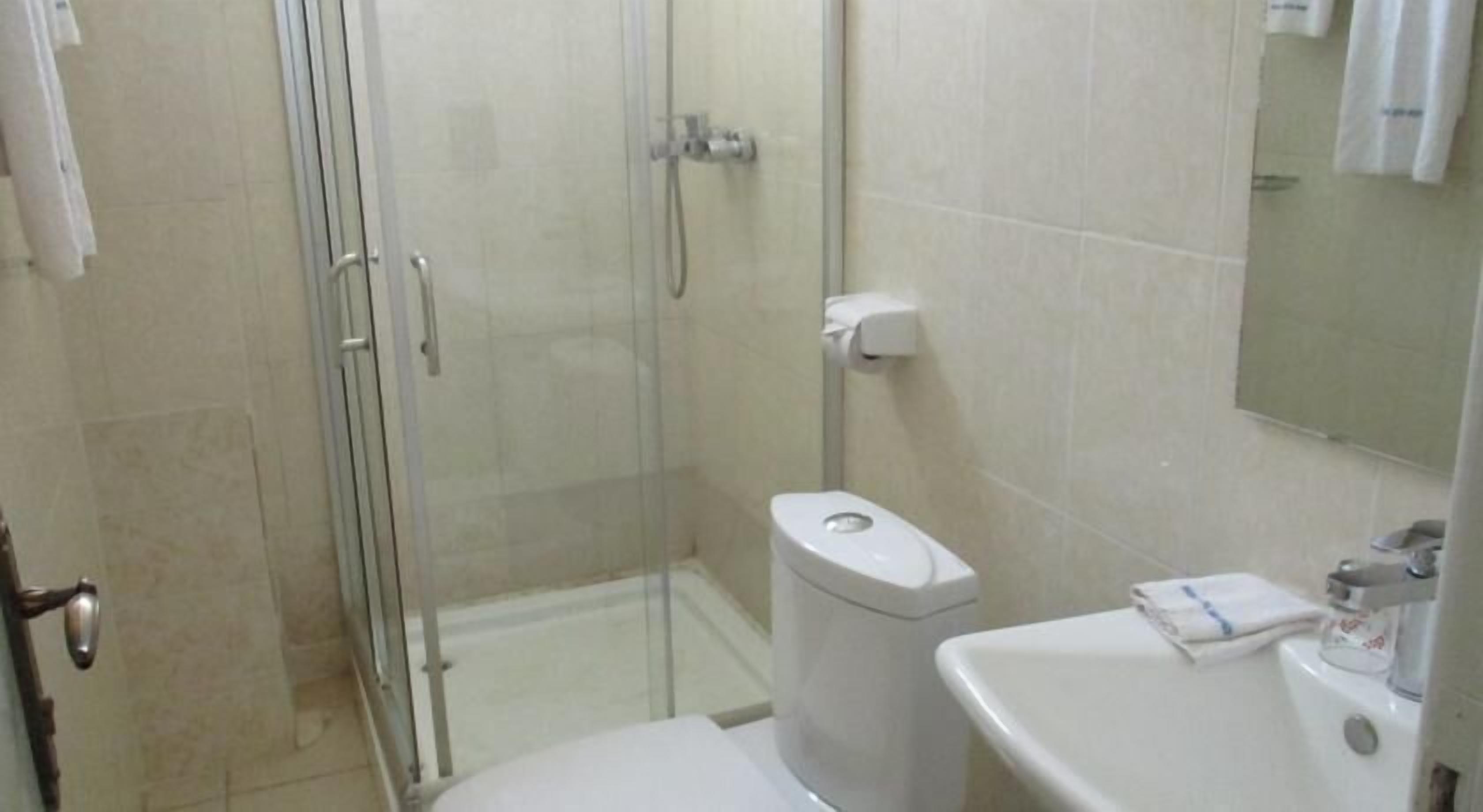 A bathroom with a glass-enclosed shower, a toilet, and a sink.