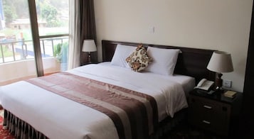 Habitación de hotel con una cama grande, dos lámparas de noche, un teléfono y vistas al exterior.